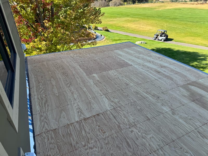 Bare plywood walk-deck substrate with perimeter edge metal flashing.