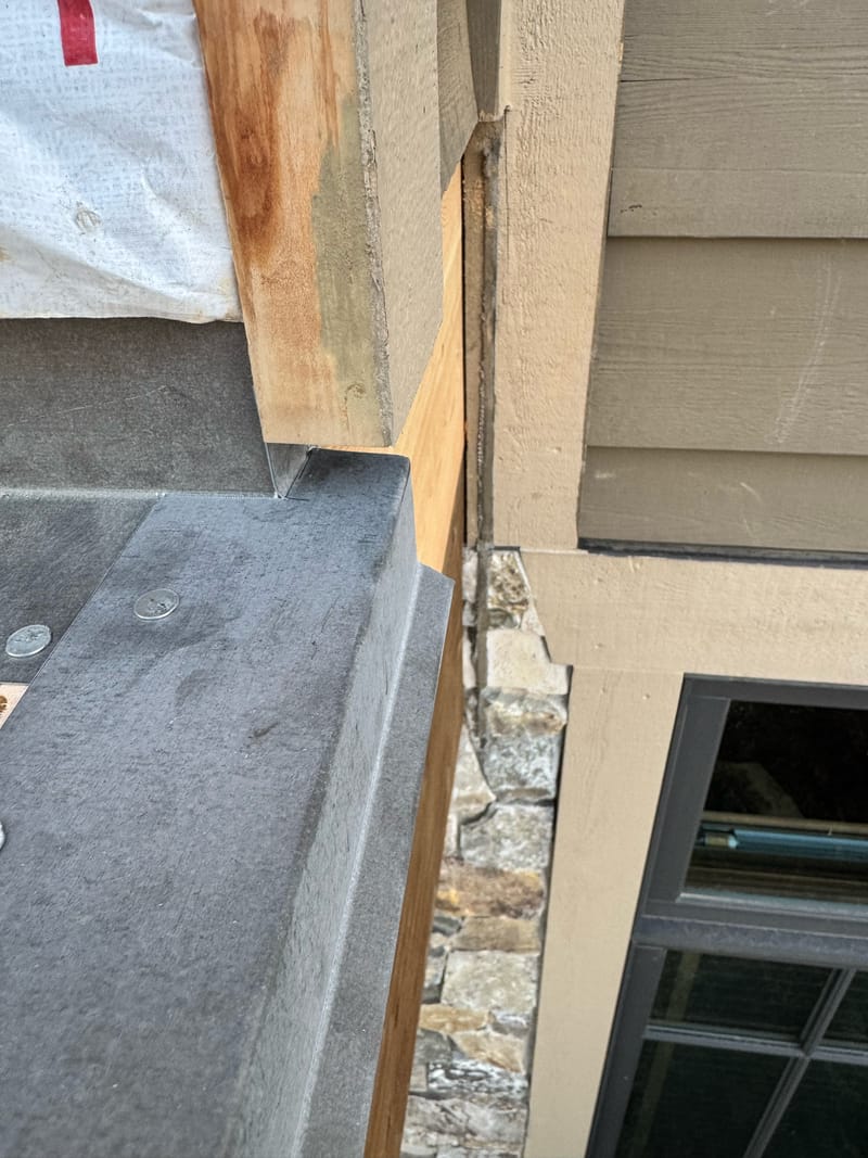 Outside-corner metal flashing at the walk-deck to wall transition.