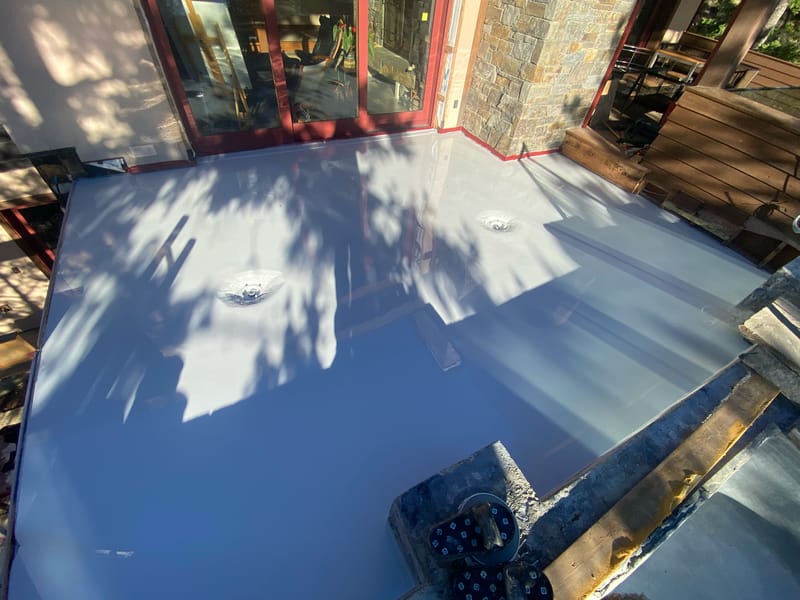 Light gray fluid-applied base coat over the primed concrete deck.