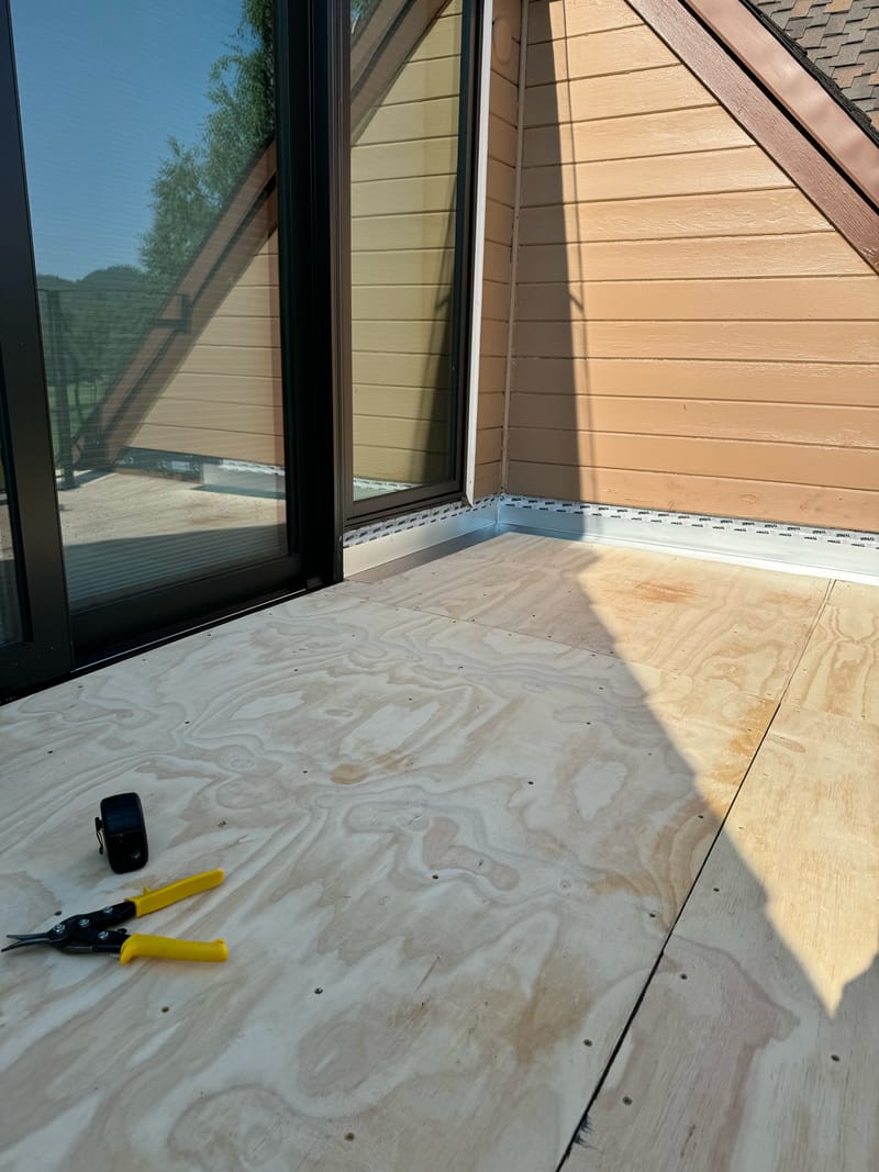 Metal wall-transition flashing and taped door threshold on the balcony.